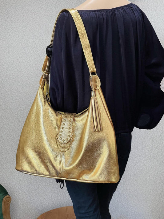 Gold metallic leather handbag brass stud feature. leather tassel and brass hardware. foam bottom to protect laptop