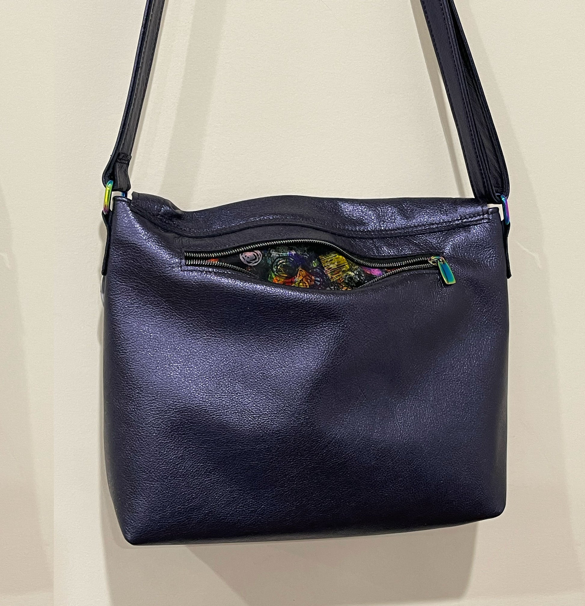 Navy blue leather handbag with floral pattern on a beige background