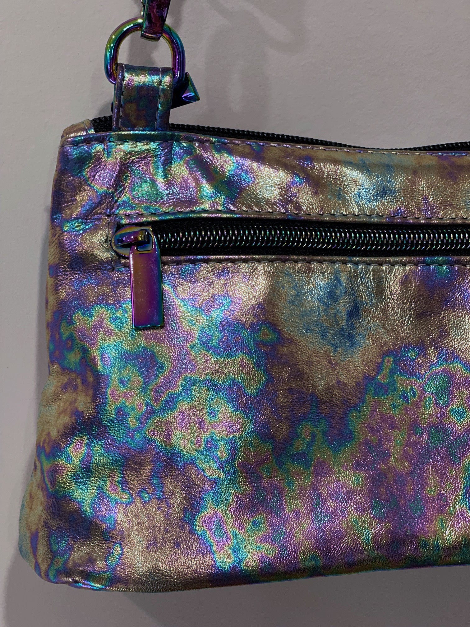 multi colour metallic pouch with a zipper pocket and zipper closure on a plain background