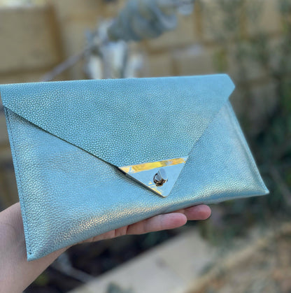 Light Turquoise blue clutch held by a hand with unique rectangle turn clasp
