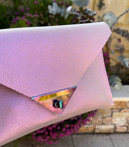 Pink clutch with a metallic clasp against a blurred natural background