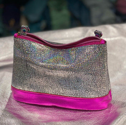 Silver textured pouch with pink zipper on a textured surface