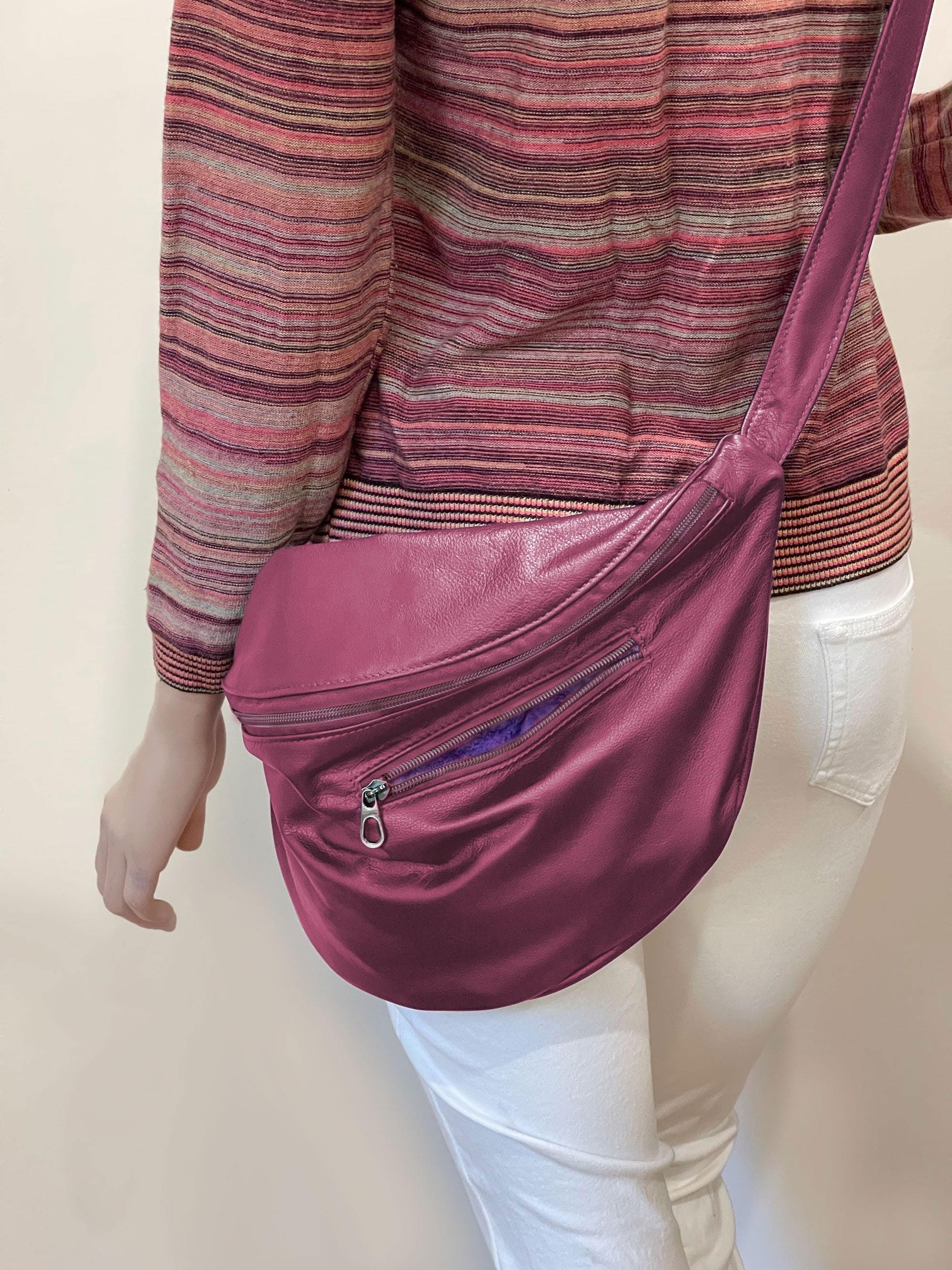 Person wearing a pink crossbody bag on a plain background