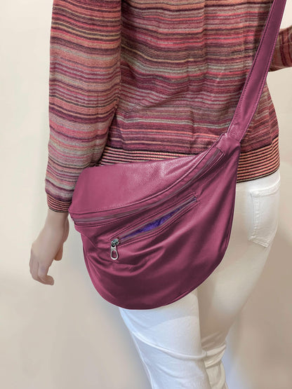 Person wearing a pink crossbody bag on a plain background