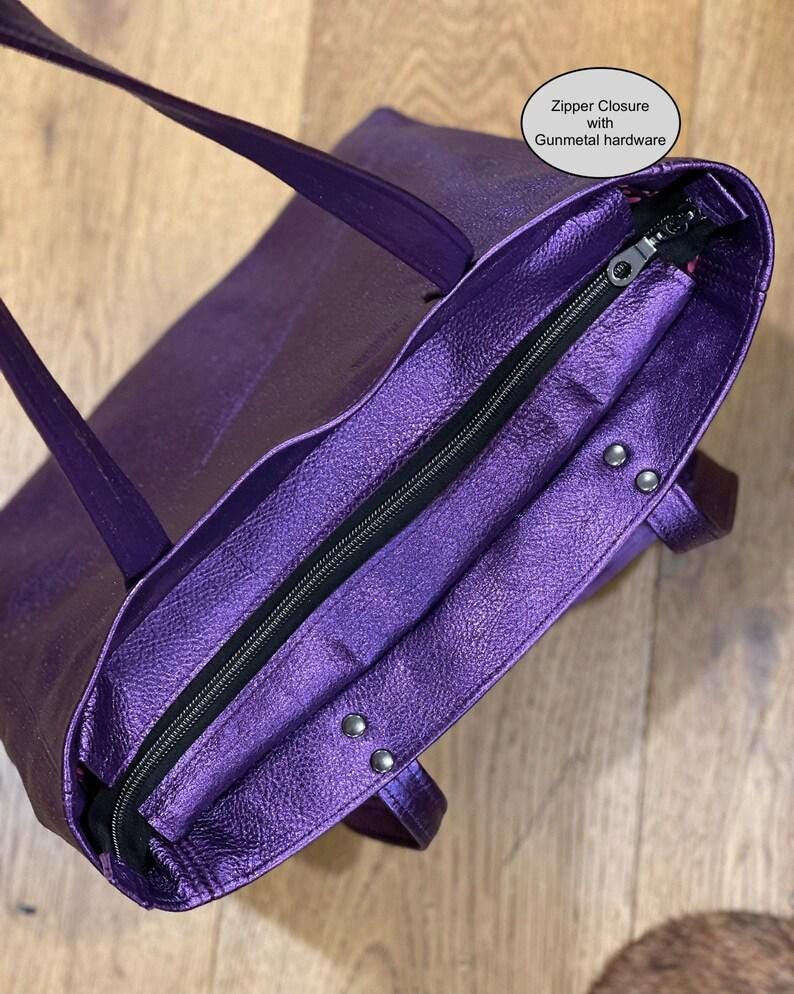Purple handbag with a zipper closure on a wooden surface