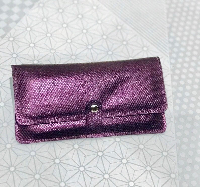 Purple textured clutch bag on a patterned white background
