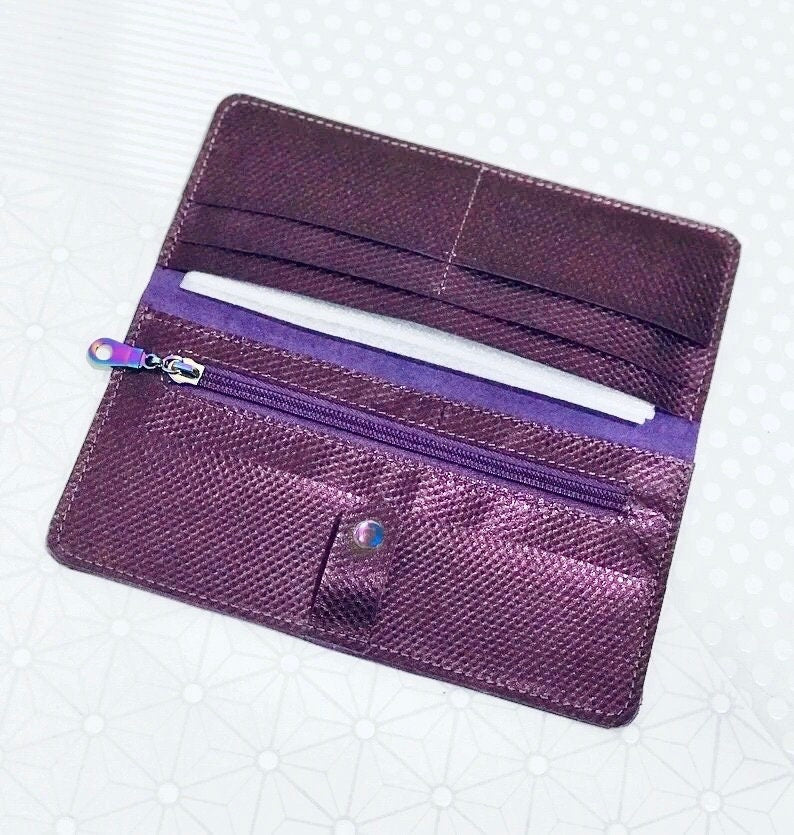 Purple wallet with a zipper on a textured white background