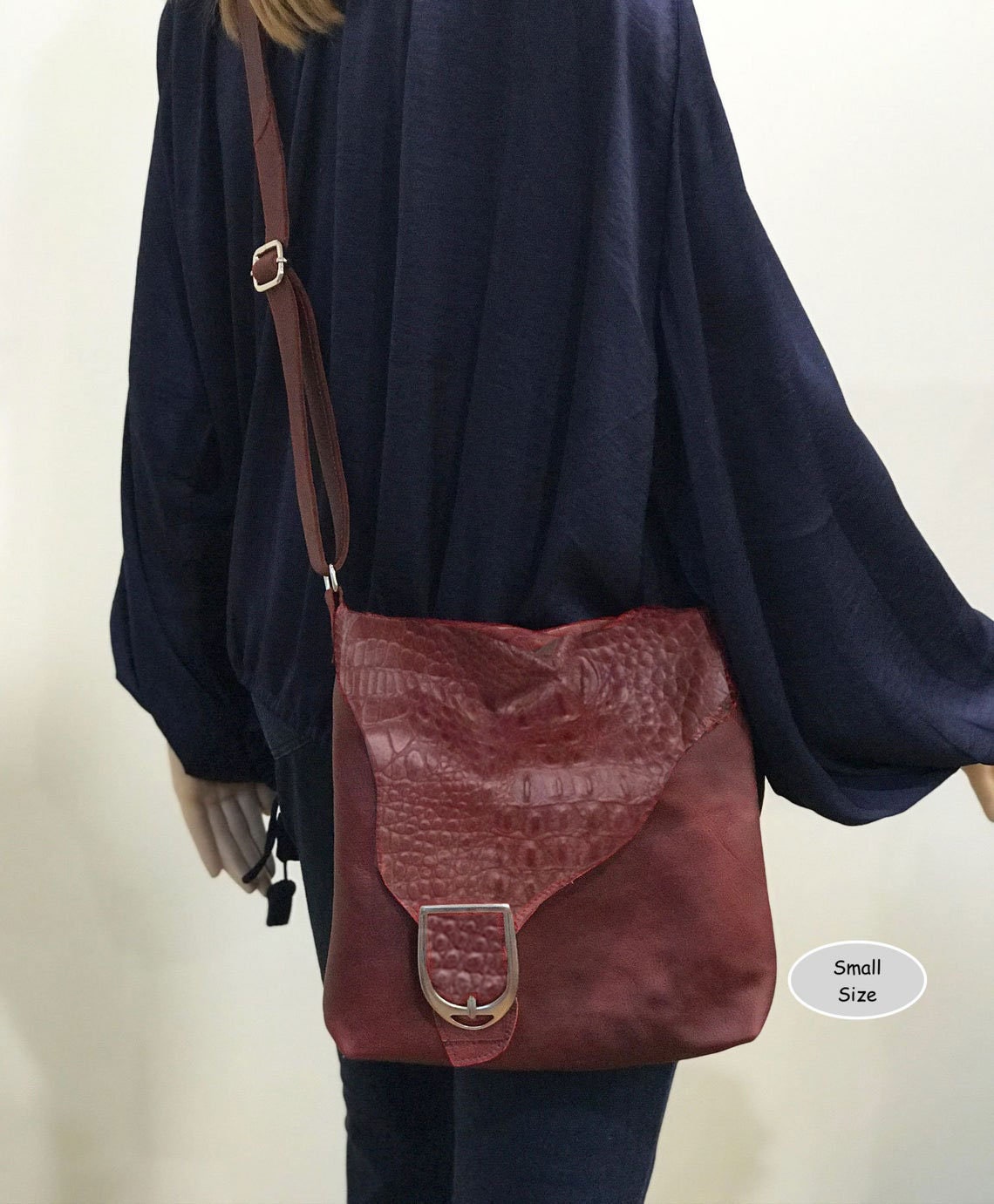 Person with a burgundy leather crossbody bag small size with croco pattern irregular flap with silver buckle