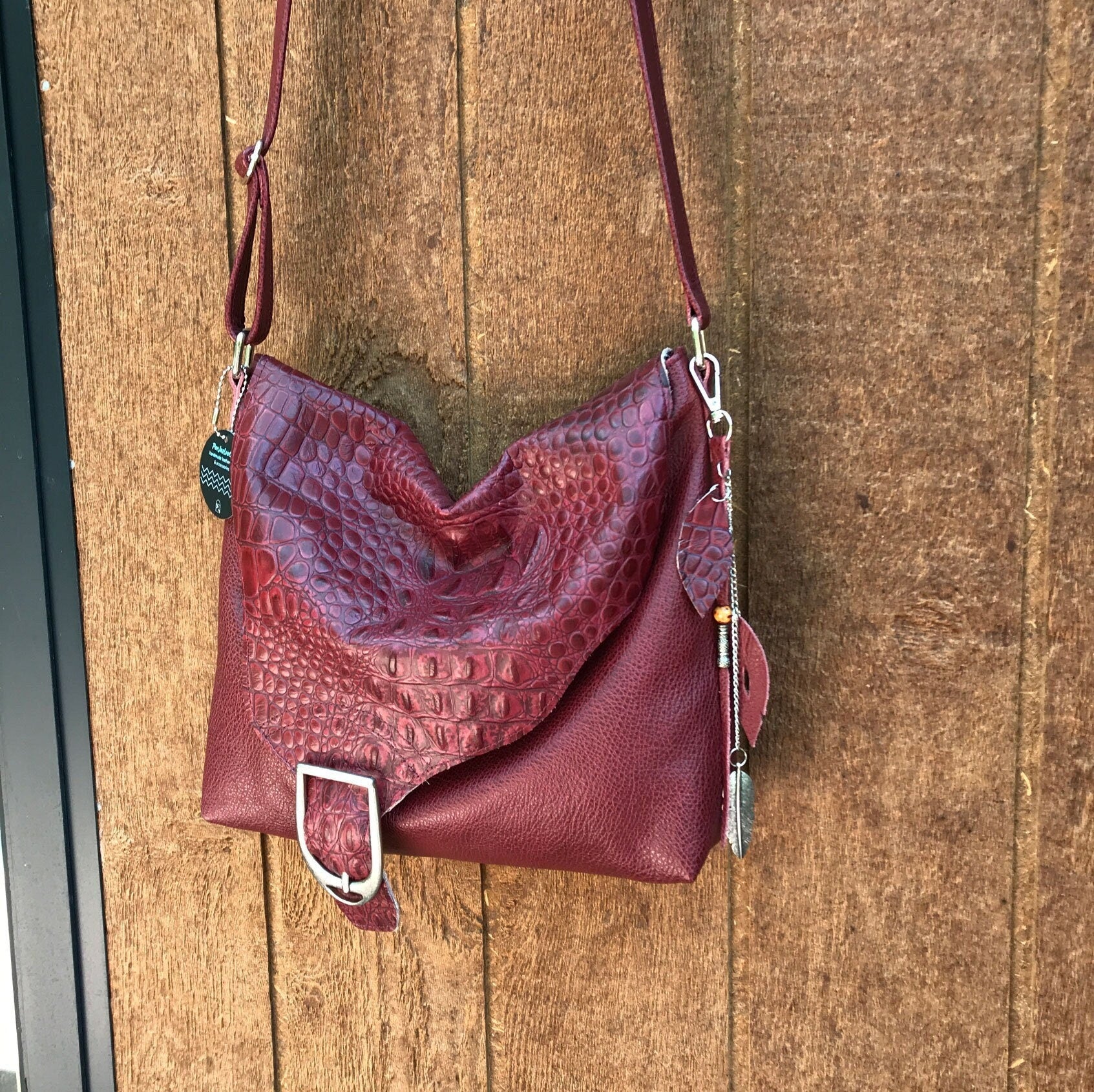 Maroon leather handbag with textured surface on a wooden surface