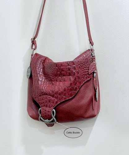 Red leather handbag with crocodile texture flap with celtic buckle on a white background
