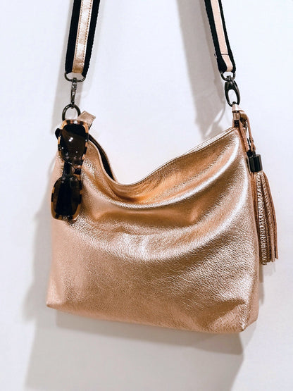 peach Gold metalli handbag with sunglasses hanging from top and a matching tassel with a black strap 