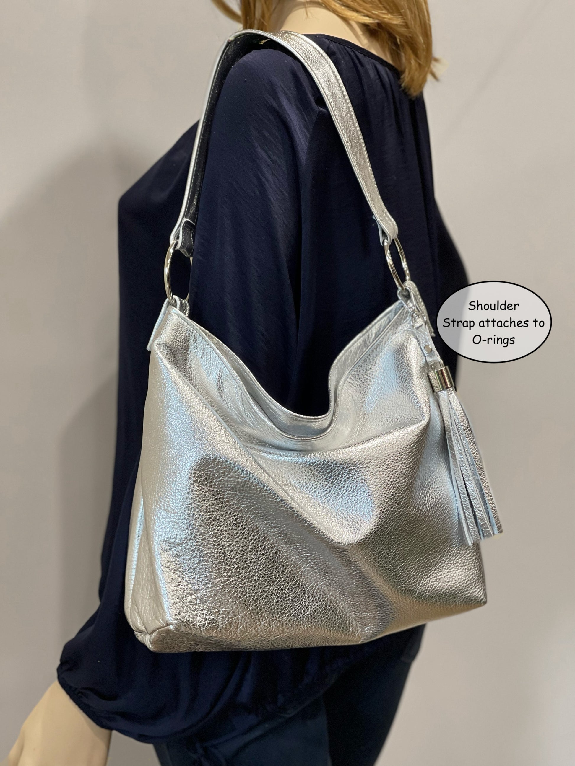 soft Silver metallic handbag with adjustable strap worn on shoulder with a tassel