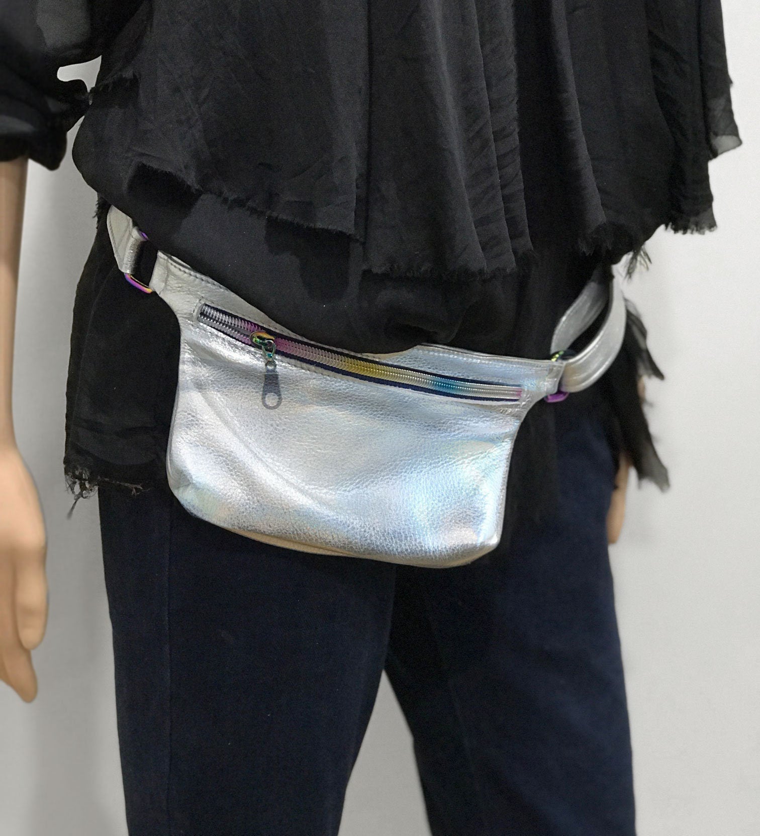 Person wearing a silver fanny pack on a plain background