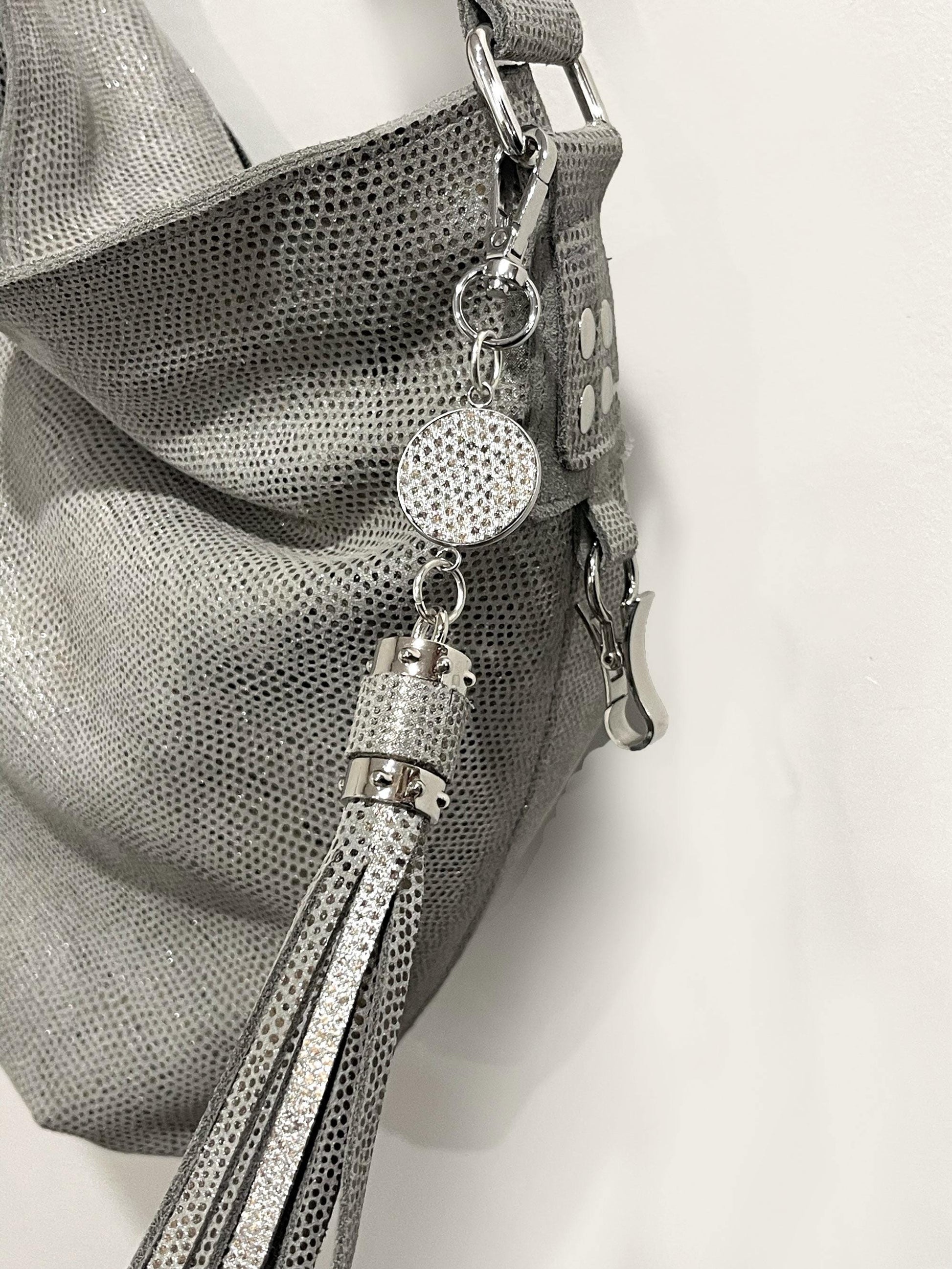 close up of a silver pearl handbag with decorative charm and tassel on a white background