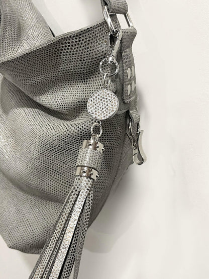 close up of a silver pearl handbag with decorative charm and tassel on a white background