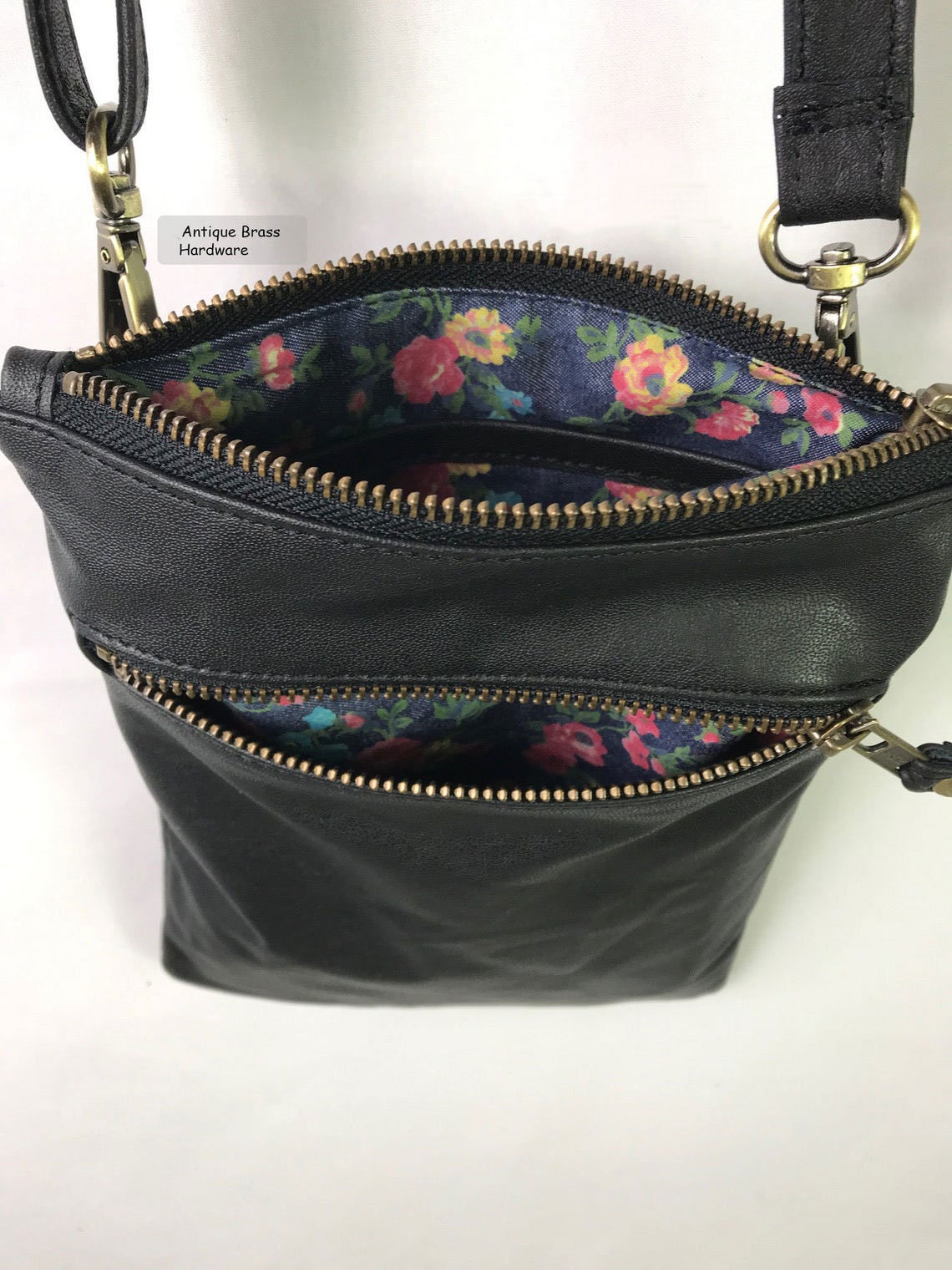 Black leather handbag with floral interior on a white background