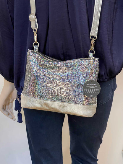 Silver textured handbag with easy over the top zipper closure, worn by a person.