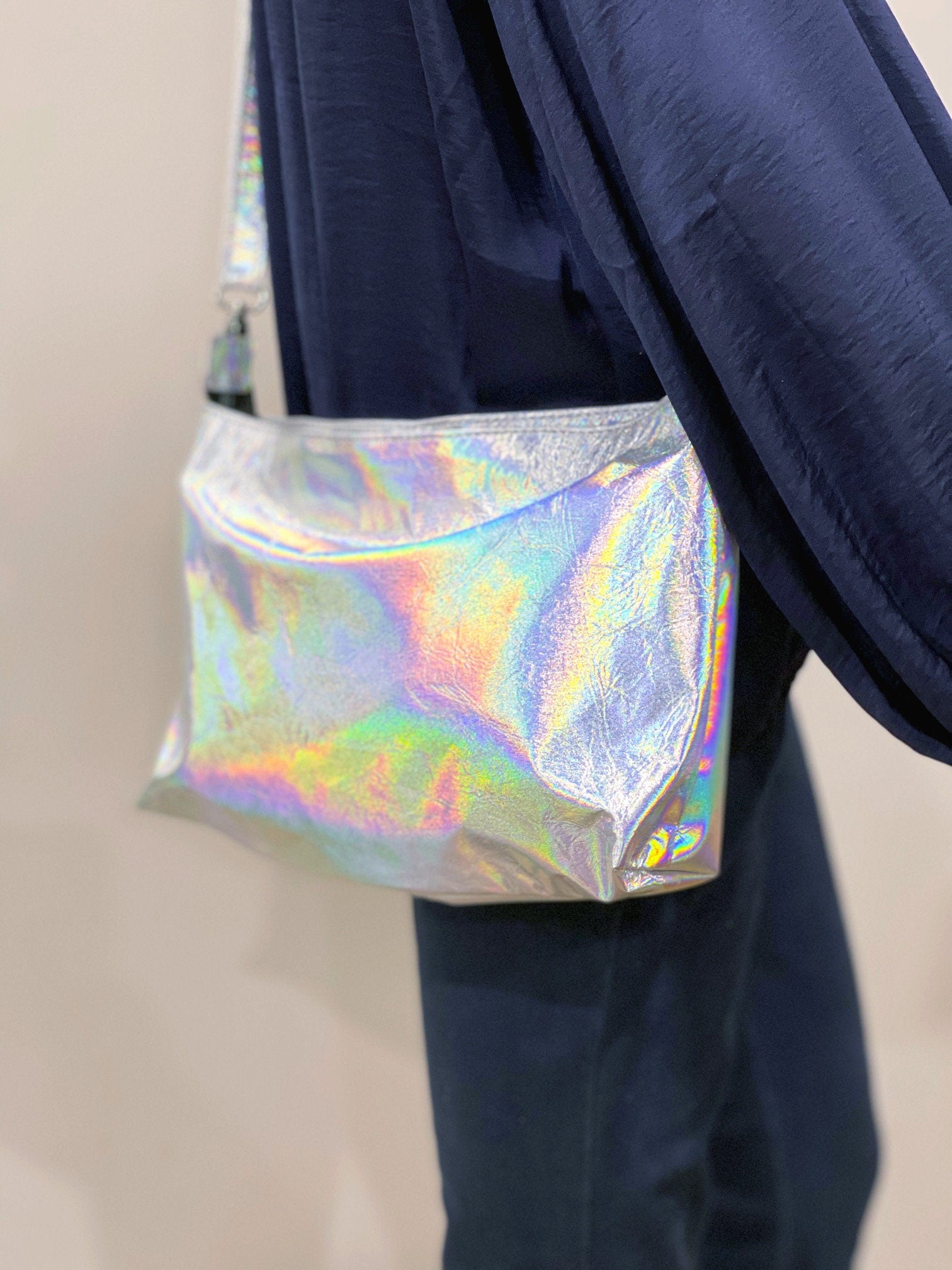Holographic shoulder bag easily worn across body for easy access shown on model wearing navy silk blouse