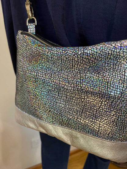 close up of small metallic iridescent bag held by a person wearing a dark blue outfit.