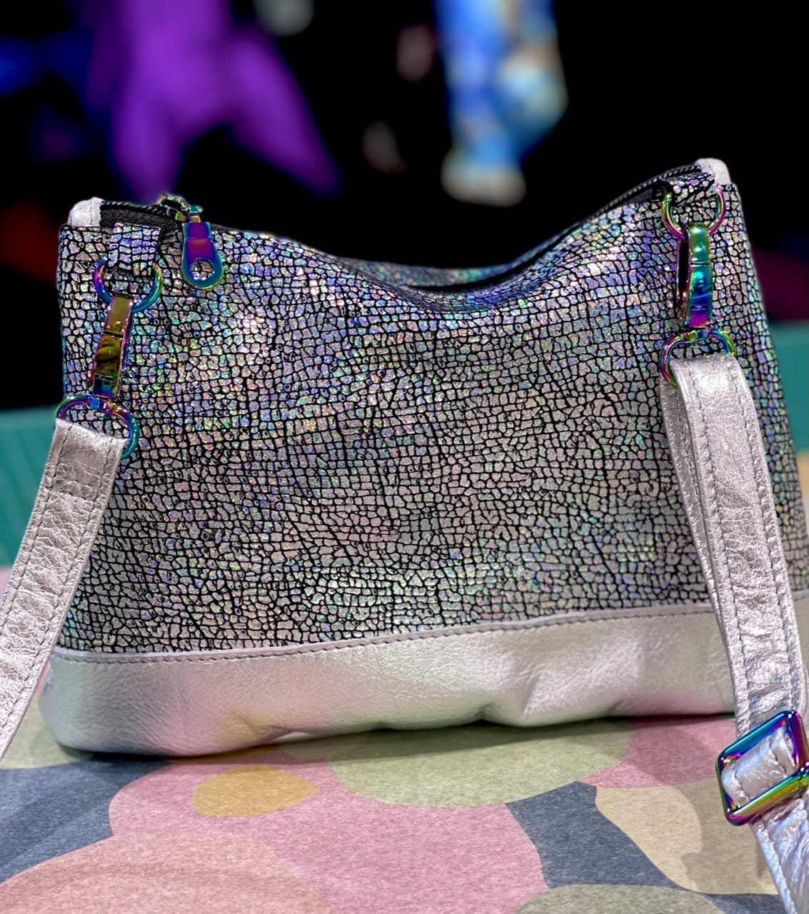 Silver textured handbag with silver metallic strap and on a paper surface