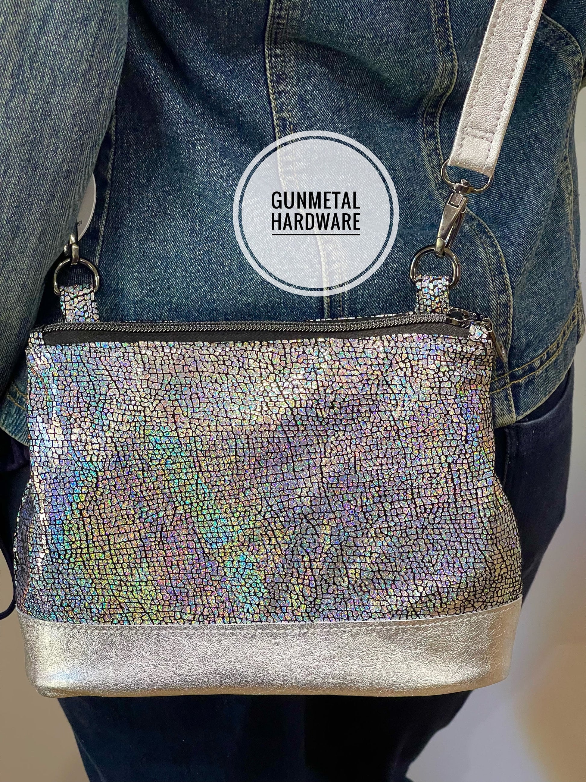 Silvery holographic textured leather handbag with gunmetal hardware on a denim background