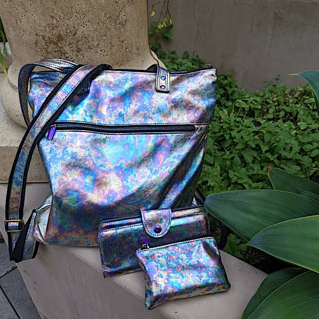 multi coloured muted design bag and wallet set on a stone surface with greenery in the background