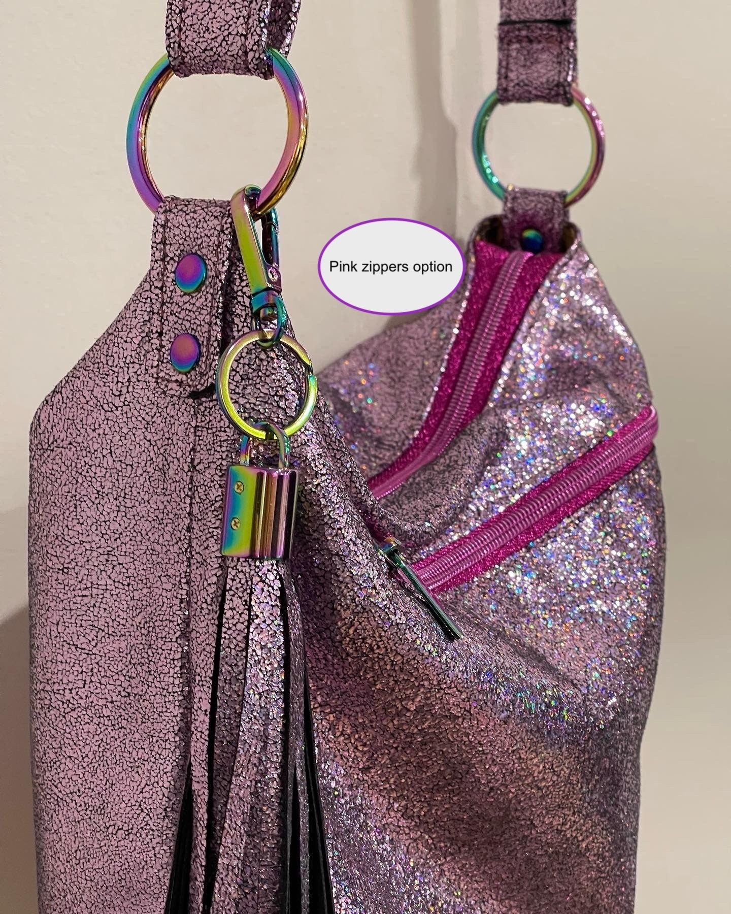 Pink glittery bag with pink zippers and colorful keychain on a beige background