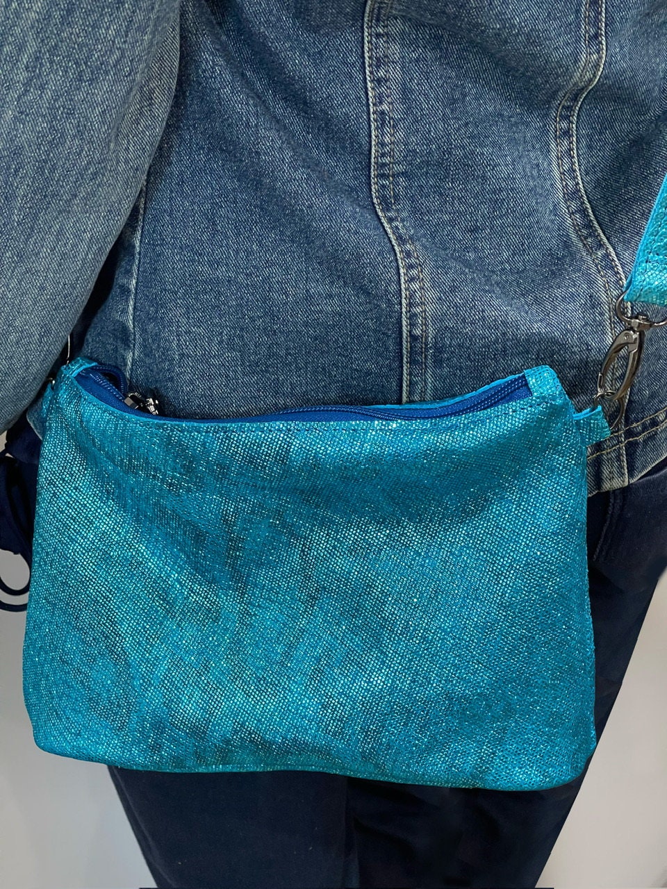Blue denim bag held by a person wearing a denim jacket and jeans.