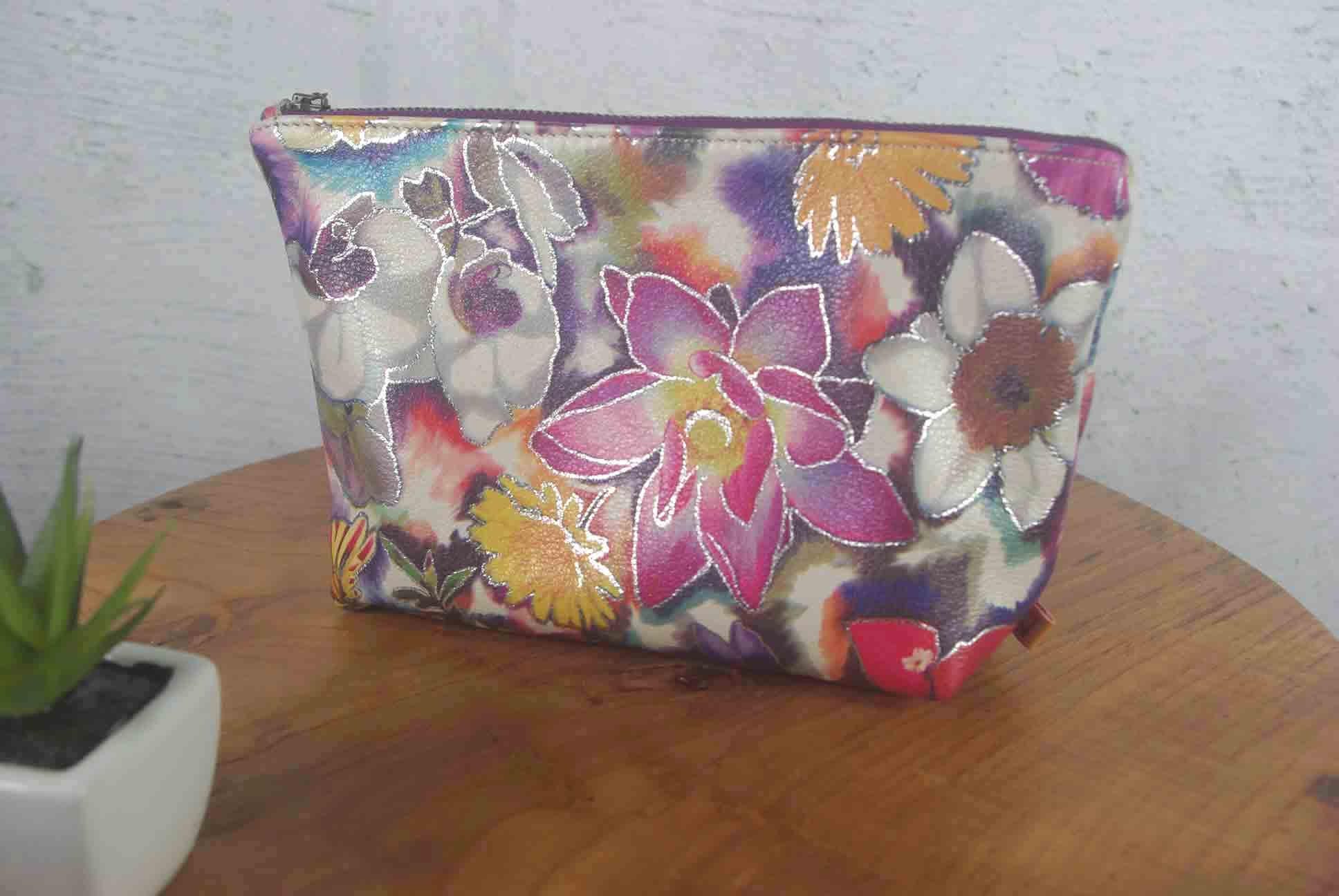 Floral-patterned pouch on a wooden surface with a white wall background