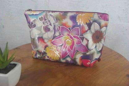 Floral-patterned pouch on a wooden surface with a white wall background