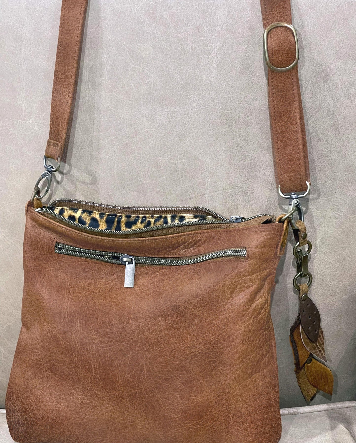 close up showing natural vintage Brown leather handbag with a leopard print interior on a light gray background