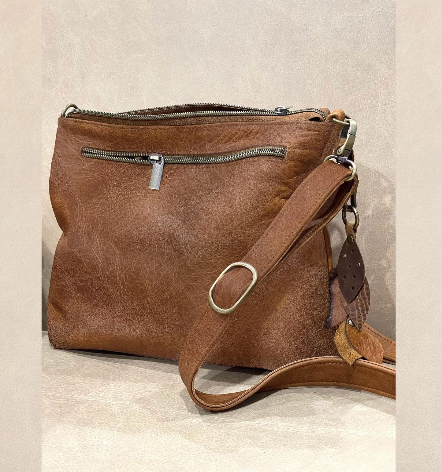 Brown leather handbag with a strap on a light background