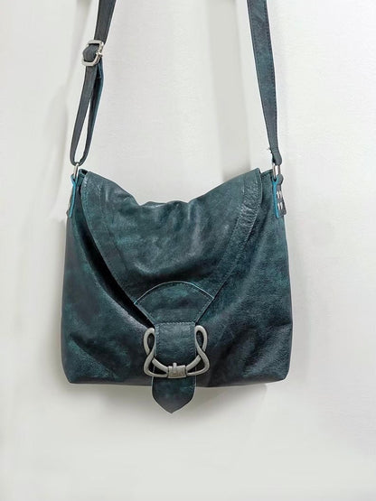 Teal leather handbag with a silver buckle on a white background